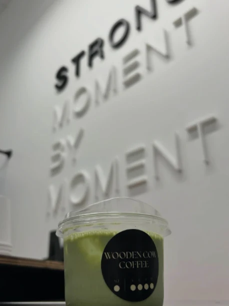 A branded iced matcha in front of a client's dimensional wall sign at a studio activation