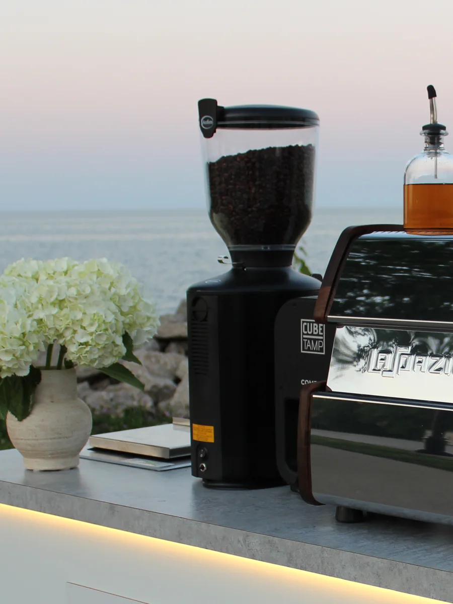 White hydrangeas beside the grinder and espresso machine on the cart counter, Lake Michigan behind